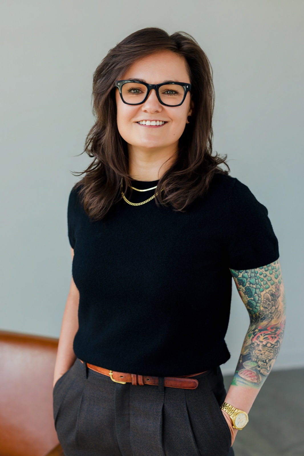 Jessica Ferrell smiling in a black top with her tattoo sleeve visible